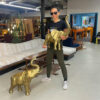 Woman holding large scale brass elephant figures over two feet tall