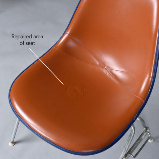 Stacking red Eames shell chair with Naugahyde pads